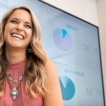 Jenna Curry in front of a TV with a presentation